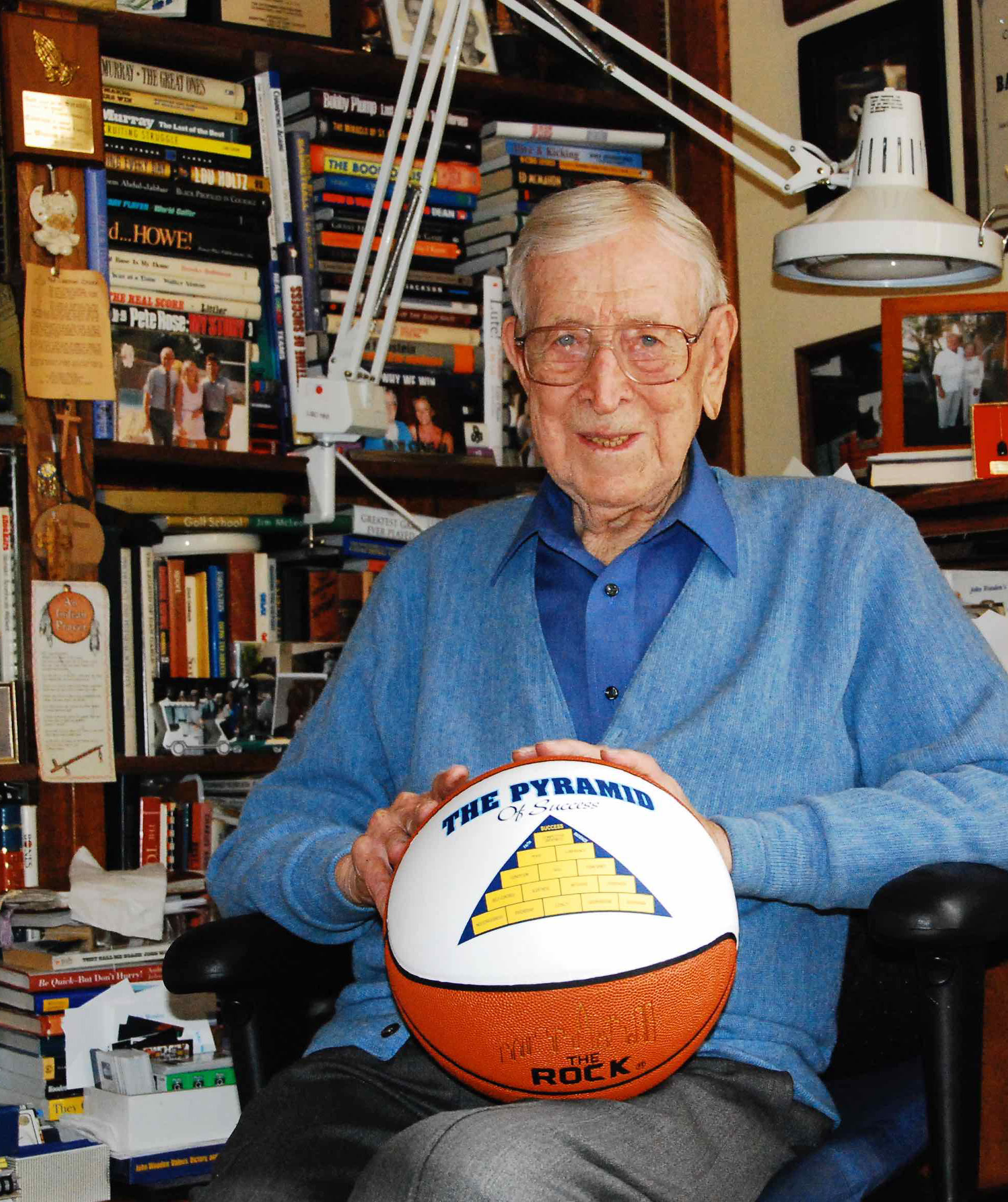 Coach Wooden iholding a basketball with his 'Pyramid of Success' printed on the ball.